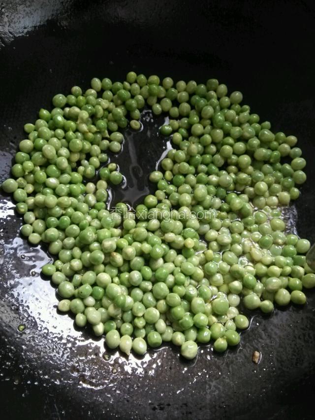 接下来锅中再倒入适量的油，不要太多了这次，倒入已经焯水过的豌豆，进行翻炒……