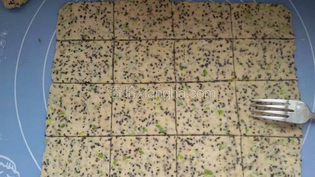在用擀面杖擀开越薄越好，用刀切下四边，在划成数个方块成饼干形壮。用叉子扎成一排排小眼。