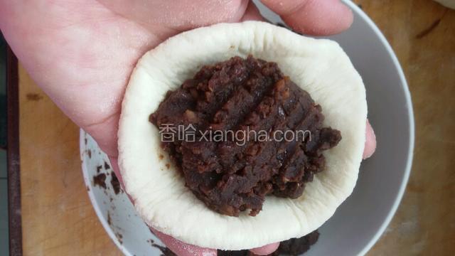 在做豆包，擀园面挤包上红豆馅捏合边缘。