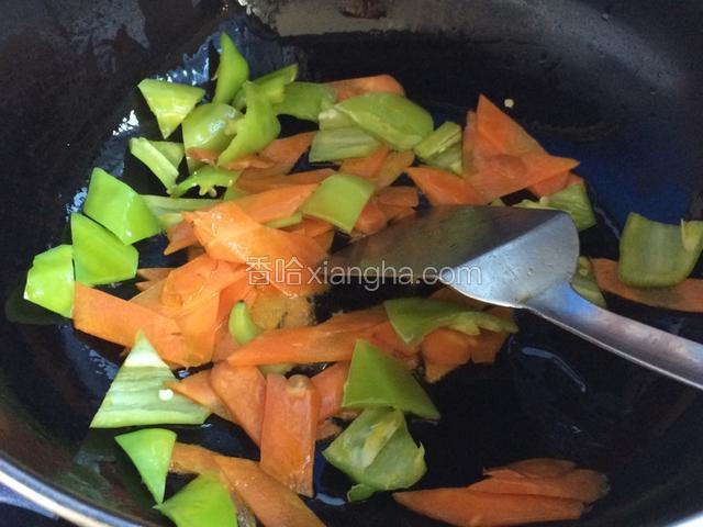 起火锅里倒适量植物油，烧至七层热时放入尖椒片胡萝卜片翻炒；