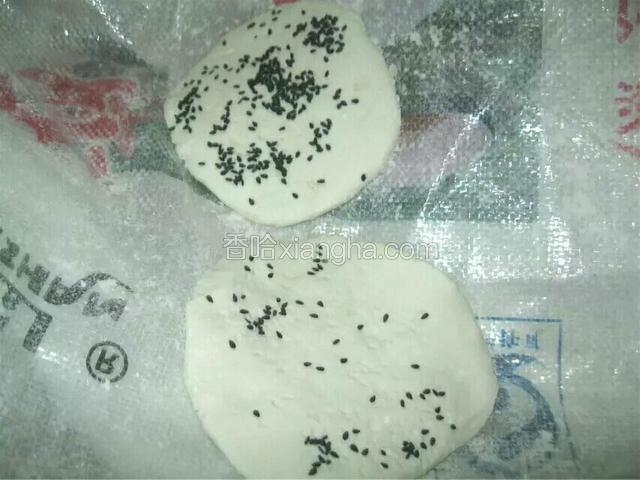 取黑芝麻按在饼上。