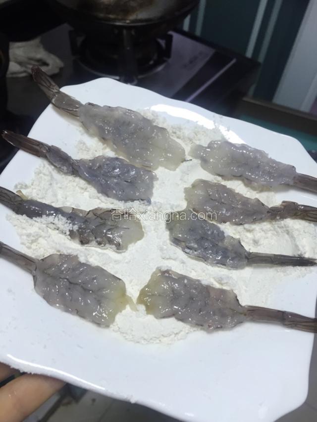 虾去头剥掉壳，用刀齐虾尾背部虾肠线划开，先双面粘上面粉