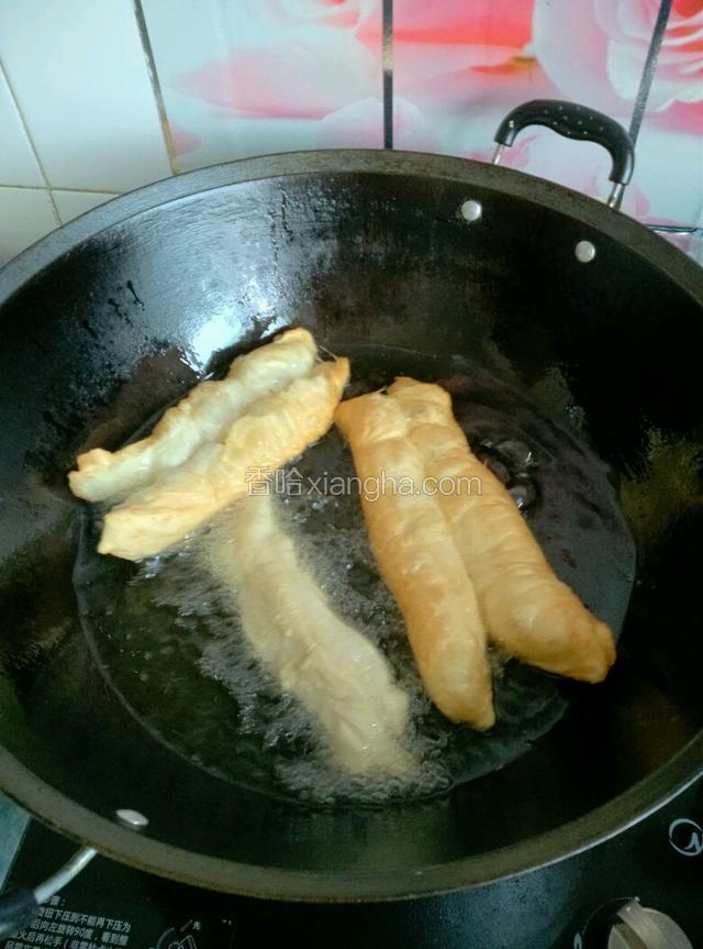 下油锅时用手把油条生坯轻轻的扯长一些，用手扯着两端，先炸中间部分，几秒钟后松手。