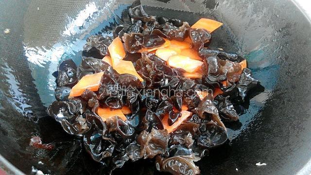 锅中放油烧热后，放入木耳和胡萝卜翻炒，倒入适量生抽和料酒快速炒匀。