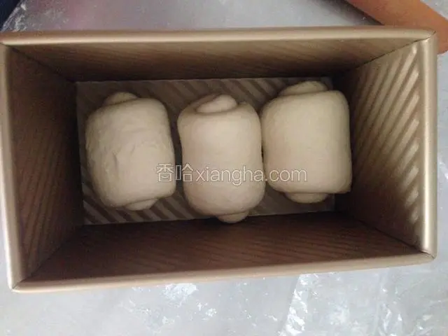 再次轻拍排气，擀长舌状，由上往下卷起。松弛5分钟。再次擀长卷起，放入模具。