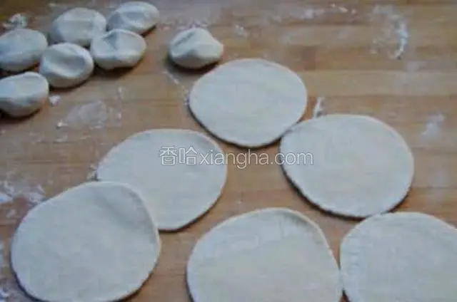 切好的小面团用手揉圆，按一下，用擀面杖擀成饺子皮