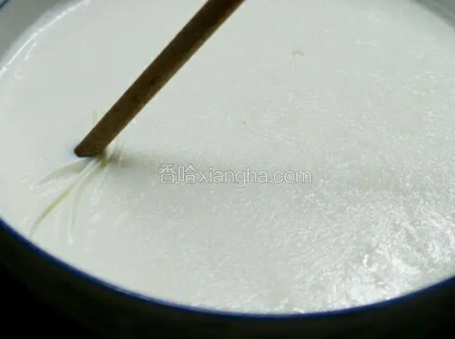 用筷子将奶皮一边稍微挑开，把牛奶倒入另一个容器，奶皮留在碗中