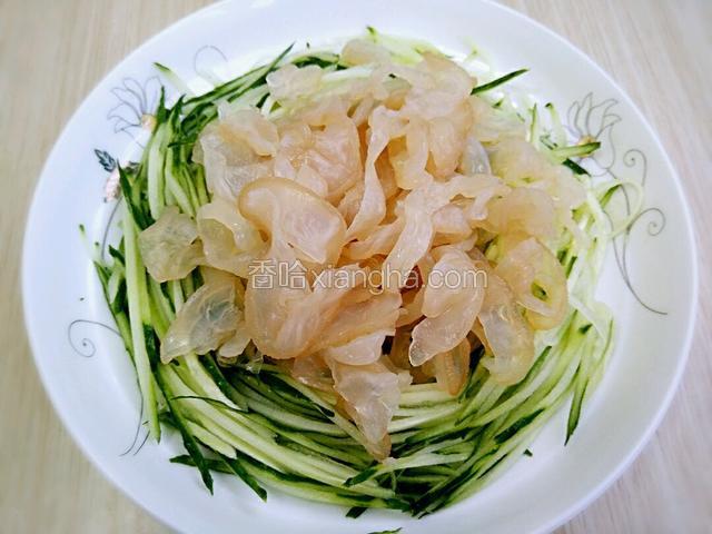 将即食海蛰丝拆开包装挤去多余的水份 随后把海蜇丝铺在黄瓜上面即可