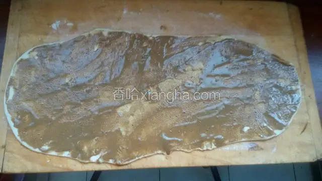 醒好面用擀面杖擀薄，擀成长圆形，抹均匀芝麻酱料