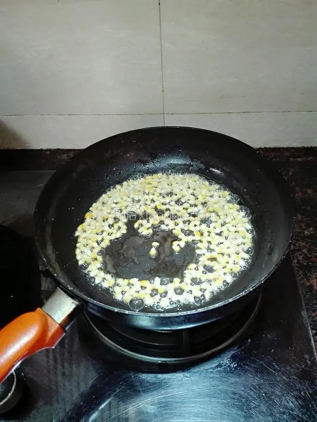 坐锅点火烧热，然后关火放入黄油融化。倒入玉米粒。晃动锅子，让每一粒玉米粒都沾上黄油