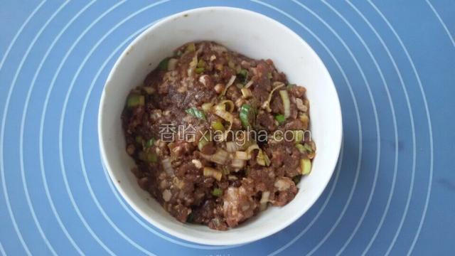 利用饧面团的时间，开始调制牛肉馅。把葱碎、姜碎、酱油和香油用筷子搅匀，再放入牛肉馅继续搅拌，另切半根葱白碎放入牛肉馅中拌匀；