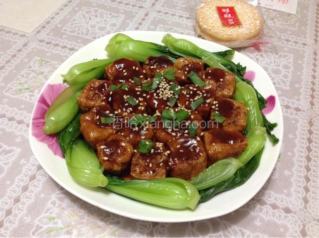 用筷子把豆腐泡一个个捡出来，肉馅面朝上，摆在盘子中间，再把锅里剩余的料汁淋在豆腐泡上，撒些葱绿和熟白芝麻点缀，香气很浓，趁热吃，外酥里嫩，酸甜可口。