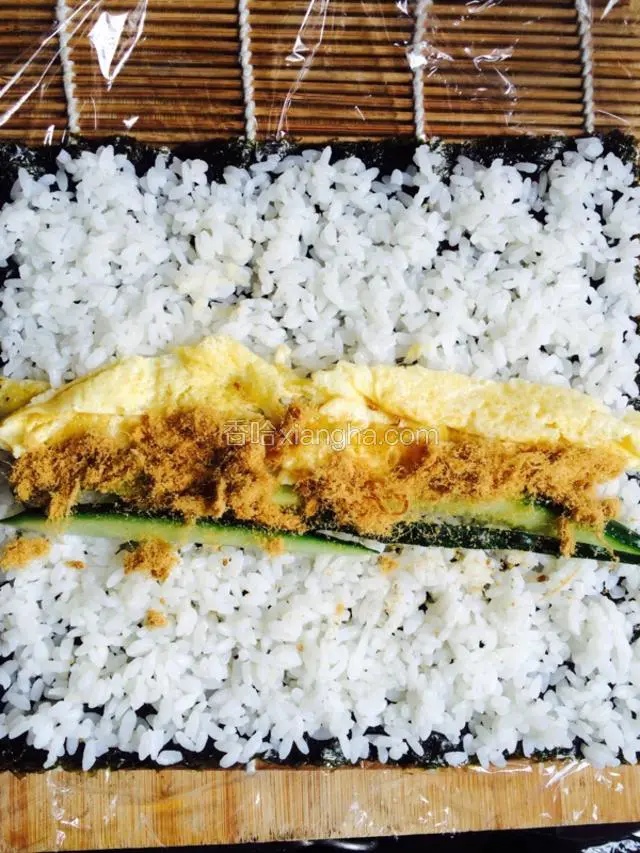 将黄瓜，鸡蛋，肉松，均匀平铺在米饭的中间部份，这可以铺在一头。