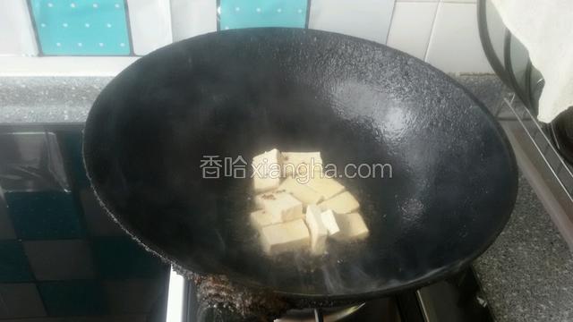 锅中放少许油，油热煸炒豆腐块表面焦黄即可