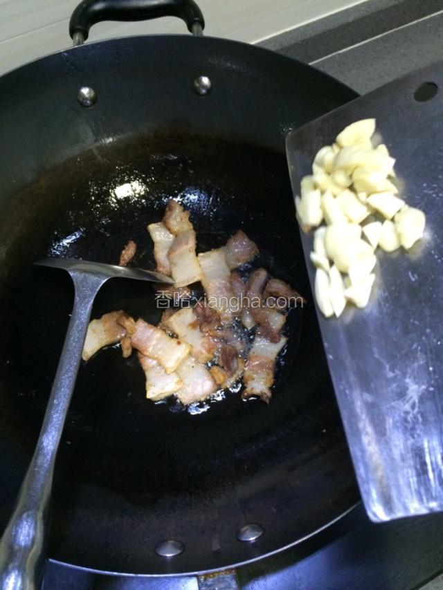 五花肉煎香后，加入蒜煸炒片刻。