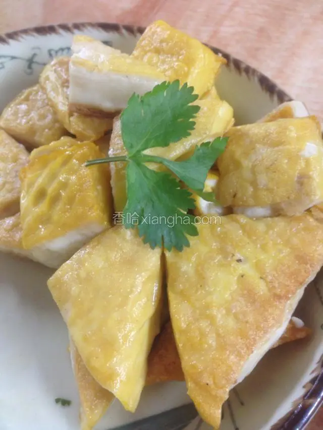 炸好的豆腐装盘，用香菜叶装饰。