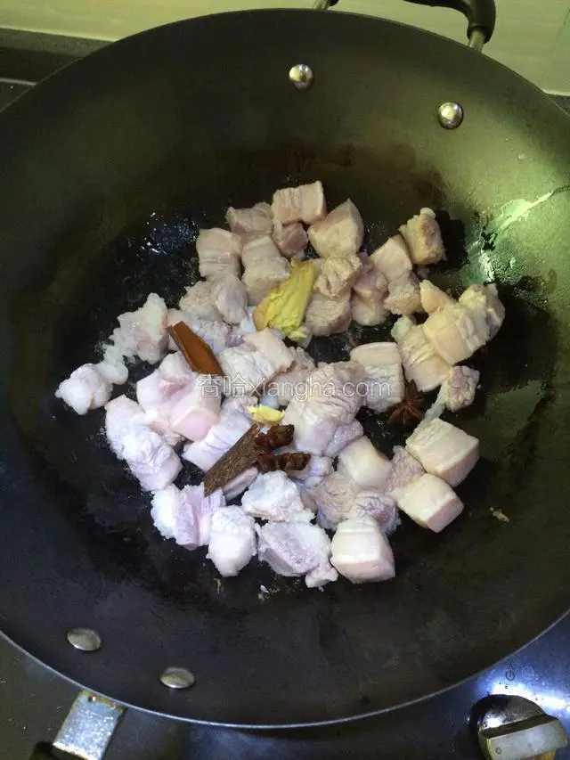 锅里倒入少许油，放入五花肉中小火煸炒，加入八角桂皮姜葱一起炒。