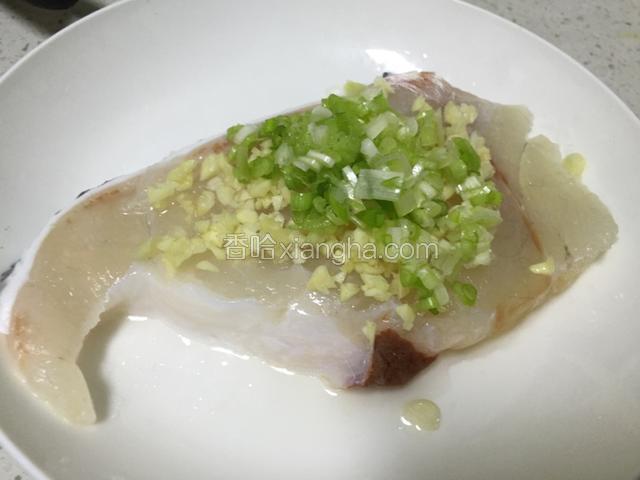 把葱末和蒜末铺在龙胆石斑鱼肉上