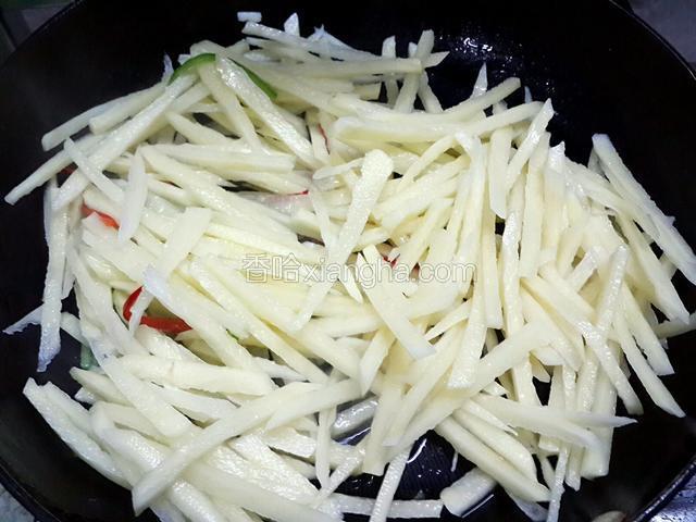 然后倒入土豆丝，翻炒约2分钟，如果感觉太干，可以适当洒点水；