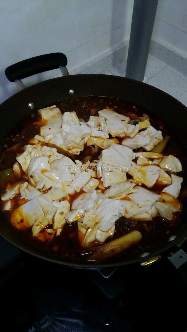 将豆腐倒入锅里，铺在鱼块上面，可以用勺子稍微压一下，争取让豆腐能浸在汤汁里面