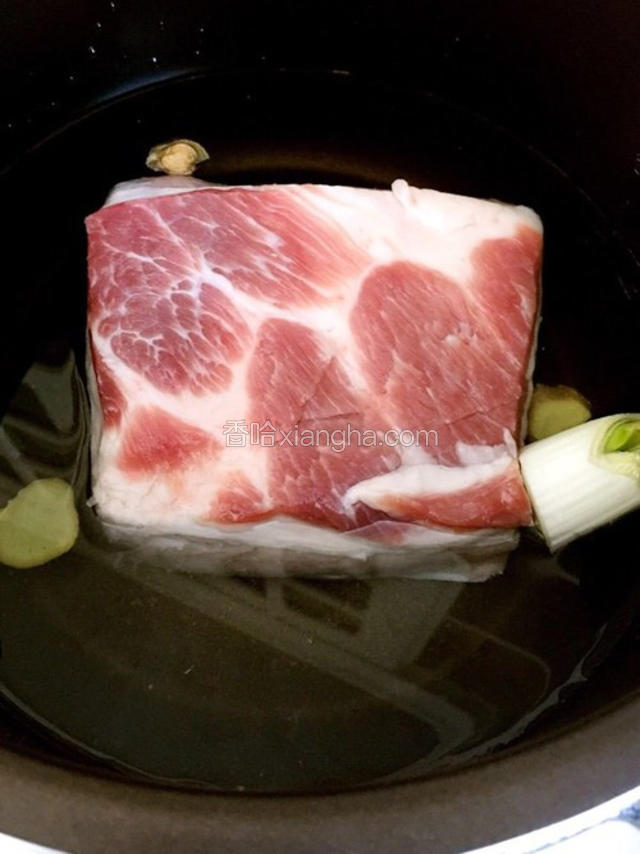 将五花肉冷水入锅，放入料酒、八角、一半的葱和姜，葱姜切成片，焯水至水沸一分钟捞出。 