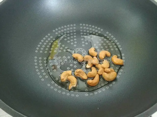 另起锅，锅中下底油，将腰果凉油下入锅中，炸至表面金黄，捞出沥油。