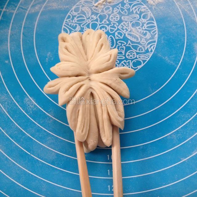 继续上面的步骤从中间掰开，然后用筷子夹住上个步骤的两个压痕，向中间夹