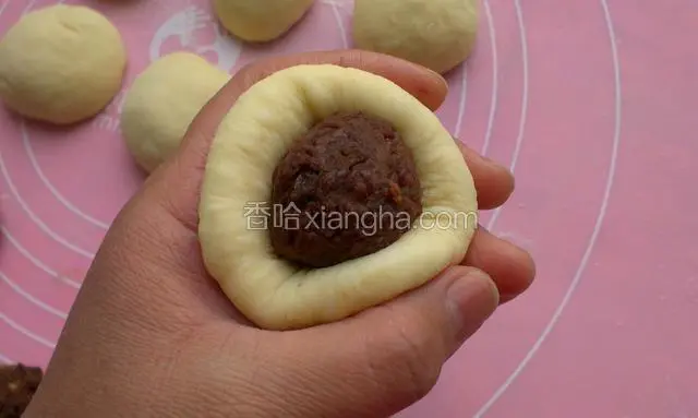 把小面团用手稍微按扁一点，包入豆沙馅