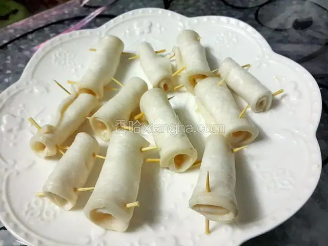 捞起后把杏鲍菇片卷成圆滚状，并用牙签固定好
