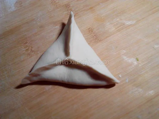 将面皮对捏起来形成三个角的形状，捏紧边缘。