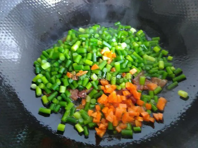 接着倒入蒜苗和胡萝卜炒匀