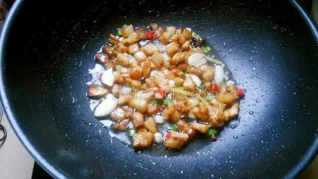 炒至肉丁变硬，倒入葱姜蒜、小米椒圈、八角、花椒炒出香味。