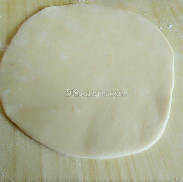 取一段从中间轻轻压扁，擀成饼皮，放入一块红豆沙，像包子一样包起