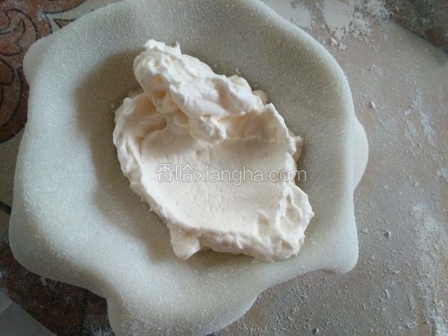 找个半圆模具托，没有就用手，把皮放模具里，放一勺奶油。（奶油在处理芒果草莓时打发，奶油加糖打发到裱花状态，放冰箱里冷藏。）