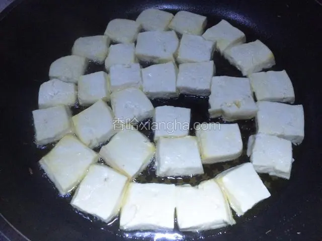 老豆腐一块，稍稍控下水分，改刀成厚度一致的小方块，摆放在蒸屉上，放置一两个小时以上，进一步控净水分。平底锅烧热后，放适量植物油，把豆腐块放进平底锅，中火慢慢煎；