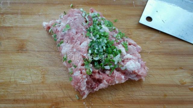 把猪肉剁碎后混入葱花一起剁成肉糜。