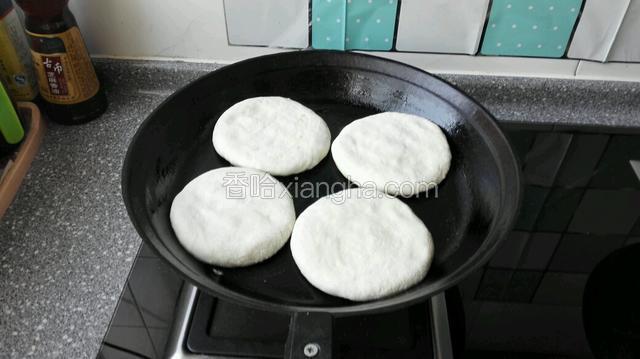 提前预热饼铛，手轻松按开饼胚正反面按开，这样两面饼皮薄厚一样，放入饼铛上小火烙制