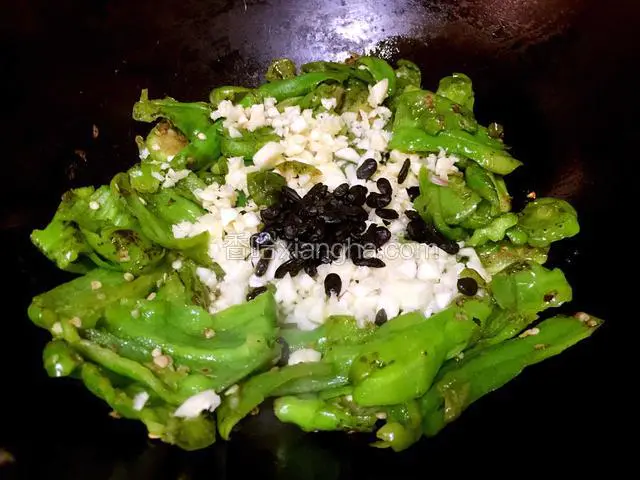煸的过程会出水，待辣椒表皮起皱，水份煸干以后放猪油爆香。加入大蒜粒和豆豉一起炒。