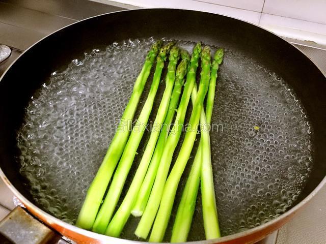 芦笋洗净削皮，放入热水中焯熟。加入适量盐和几滴油让芦笋更嫩绿。