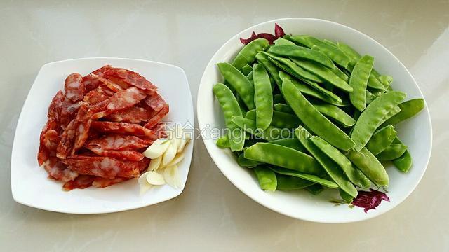 准备食材，荷兰豆撕去筋膜洗净，腊肠和大蒜切片备用。