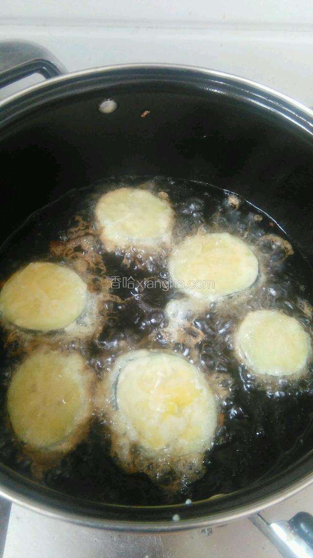 锅内放入食用油，放入裹好蛋液的茄子。炸至一面金黄。