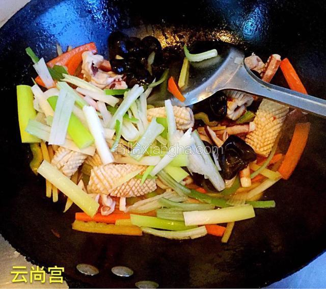 鱿鱼倒进锅里快速翻炒。最后加入葱条翻炒。