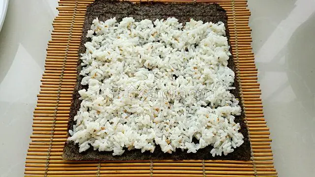 把米饭均匀的铺到紫菜上，上面留一条不放米饭。