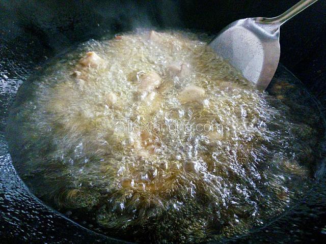 锅中倒多点油烧到很热，倒入腌好的鸡肉块炸。