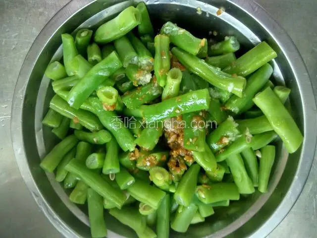 把调好的蒜汁倒入四季豆里，留一些蒜泥在最后放。