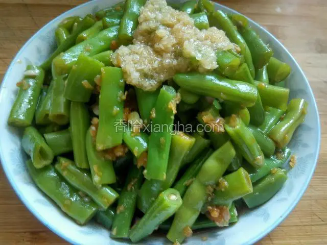 把调好的四季豆放入盘子里，把蒜泥放在四季豆上边装饰一下。