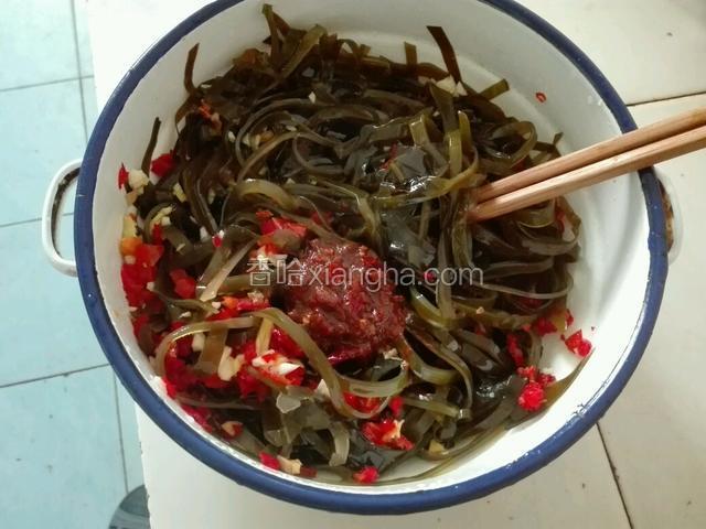拿一个大碗，放入海带丝。加红辣椒大蒜姜未适量盐、老抽、2勺麻辣香水鱼调料、少许味精。