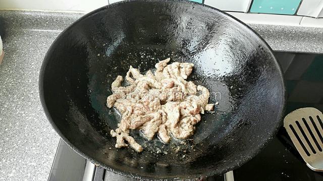 热锅凉油下入腌好牛肉条，煸炒段生变色