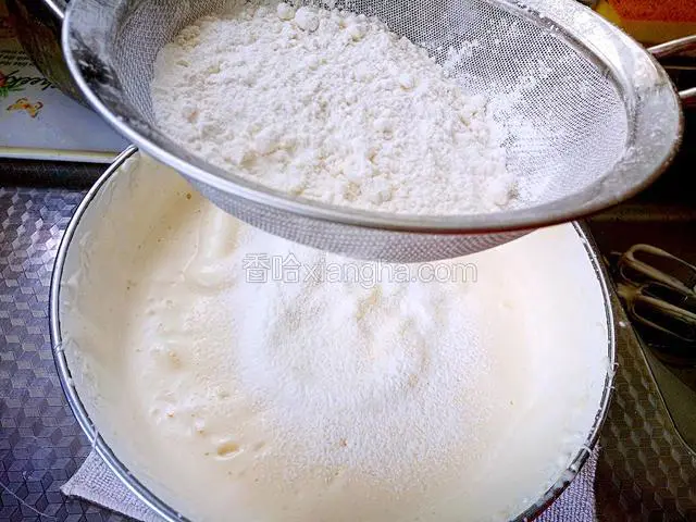 此时把低筋粉和泡打粉混合物过筛到蛋糊中