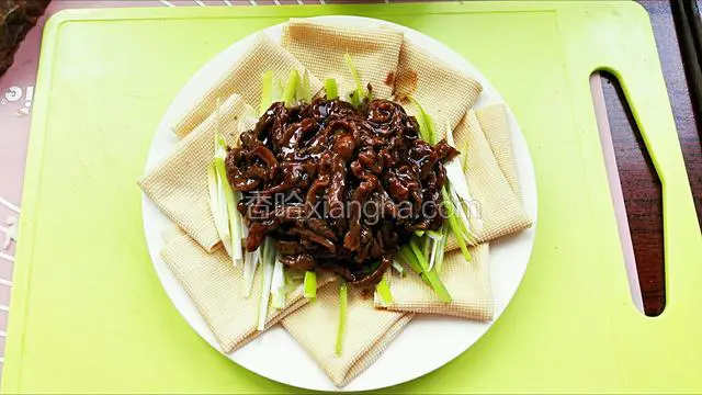 然后用出锅将肉丝趁热放入葱丝上，用牛肉丝热度烫出葱香味即可完成